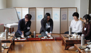 Students are kneeling down on the floor, pouring tea to the tea porcelain